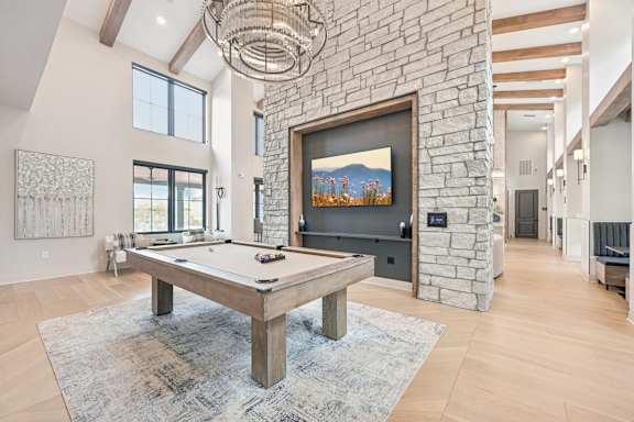 A pool table is in the middle of a room with a stone wall and a painting hanging above it.at The Garrison Luxury Apartment Homes, Fountain