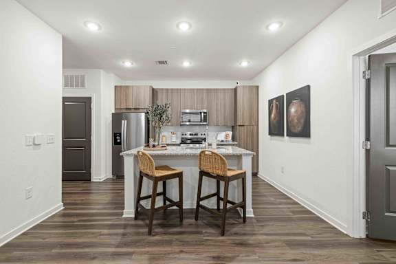 A kitchen with a white countertop and brown bar stools. at Terrassa Luxury Apartments, St. Augustine, 32084
