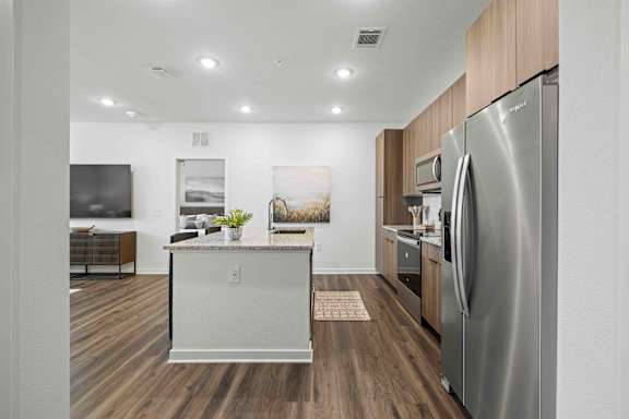 A modern kitchen with a stainless steel refrigerator and wooden flooring. at Terrassa Luxury Apartments, St. Augustine, Florida