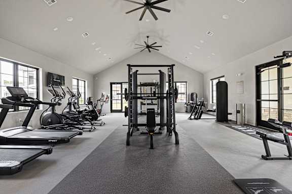 A spacious gym with treadmills, elliptical machines, and a weightlifting area.at The Levi Luxury Apartments, McDonough