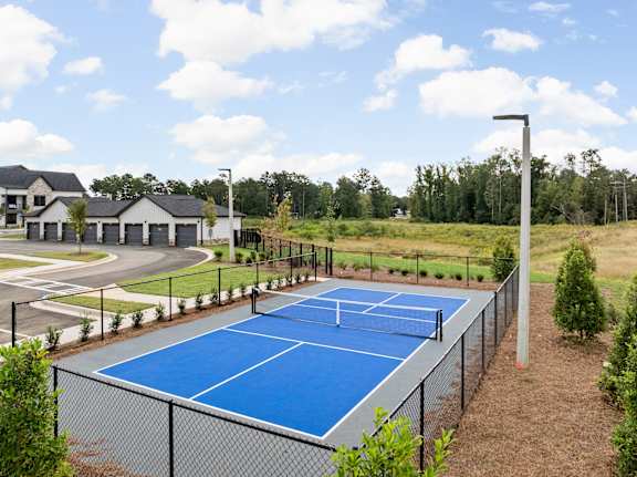 A blue tennis court surrounded by a black fence.at The Levi Luxury Apartments, McDonough