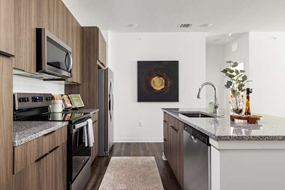 A modern kitchen with a dark wood finish.at The Levi Luxury Apartments, McDonough