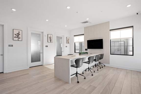 A modern office space with a desk, chairs, and a television. at The Maddox Luxury Apartments, Buckeye, 85326