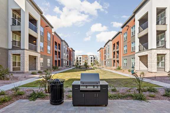 A bbq grill is in the middle of a courtyard surrounded by apartment buildings. at The Maddox Luxury Apartments, Buckeye, 85326