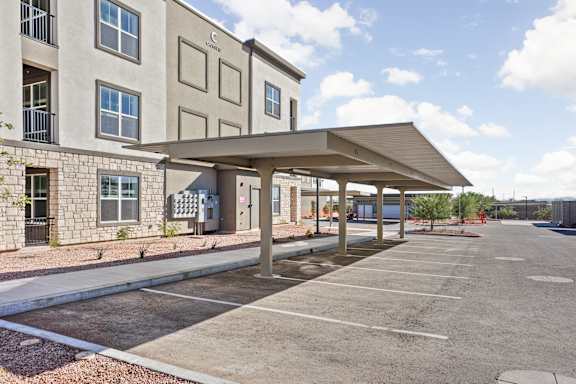 A parking lot in front of a building with a covered walkway at The Maddox Luxury Apartments, Buckeye, 85326