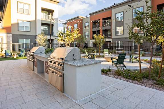 A modern outdoor kitchen with a grill and sink. at The Maddox Luxury Apartments, Buckeye, 85326
