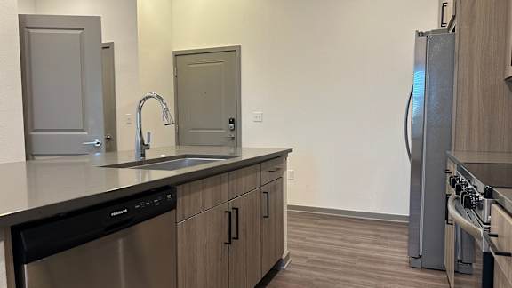 A kitchen with a stainless steel dishwasher and a refrigerator.