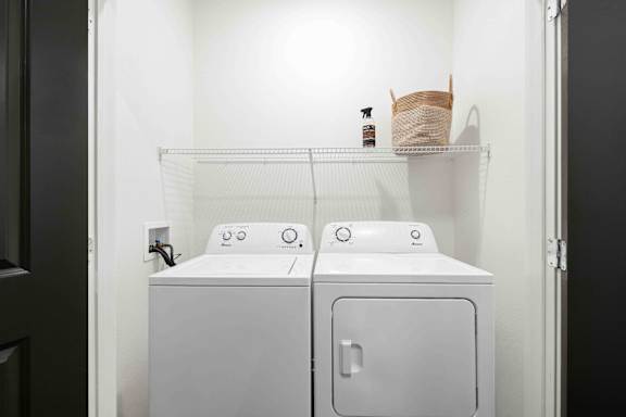 A white washing machine and dryer in a small laundry room at Verity Luxury Apartments, Florida 32960
