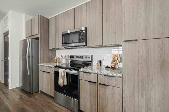 A modern kitchen with wooden cabinets and stainless steel appliances at Verity Luxury Apartments, Vero Beach
