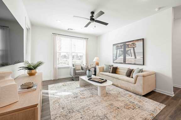 A living room with a beige couch, a rug, and a painting on the wall at Verity Luxury Apartments, Vero Beach, FL