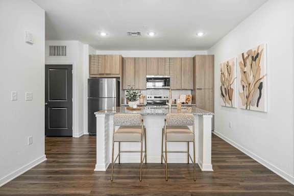 A kitchen with a refrigerator, oven, and a counter with two chairs at Verity Luxury Apartments, Vero Beach
