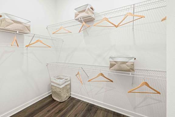 A white closet with orange hangers and a trash can at Verity Luxury Apartments, Vero Beach