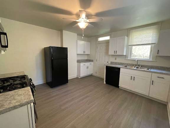 A kitchen with a black fridge and white cabinets.