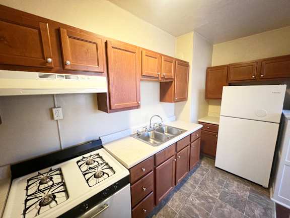 A kitchen with white appliances and brown cabinets.