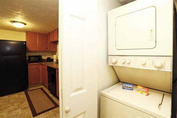 A black refrigerator is in a kitchen with brown cabinets.