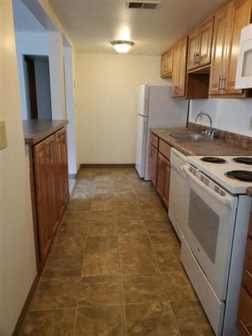 A kitchen with a white refrigerator and a white stove top oven.