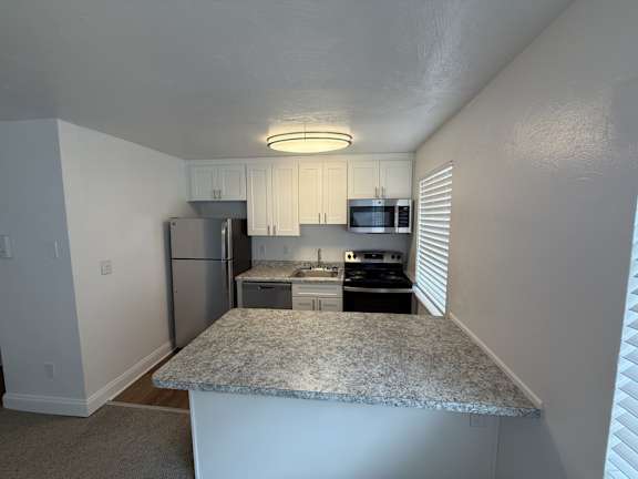 A kitchen with granite countertops and white cabinets.