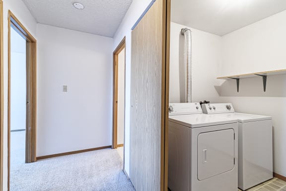an empty laundry room with a washer and dryer in it and a door