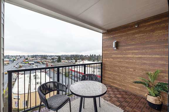 A balcony with a table and chair overlooking a street.