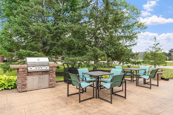 A patio with a table and chairs and a grill.