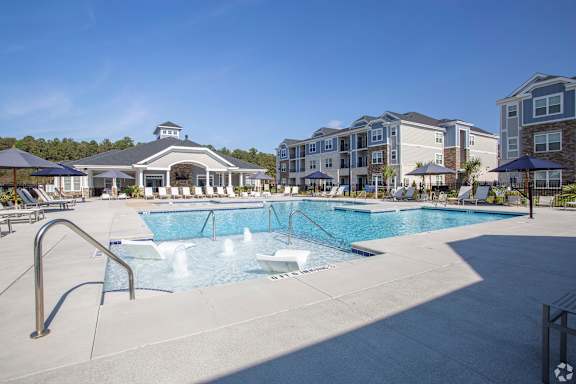 A large swimming pool with a slide and a building in the background.