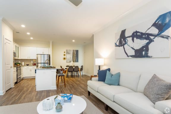 a living room with white walls and a white couch with blue pillows at Fuquay-Varina Apartments, North Carolina
