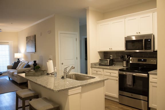 a kitchen with white cabinets and a granite counter top  at The Retreat at Sumter, Sumter, South Carolina