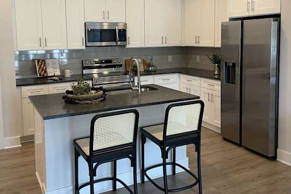 A modern kitchen with a stainless steel refrigerator and a black chair.