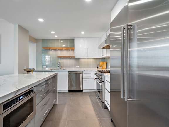 A modern kitchen with stainless steel appliances and white cabinets.