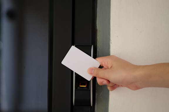 A hand holding a card is about to insert it into a slot.