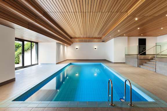 A large indoor swimming pool with a wooden ceiling.