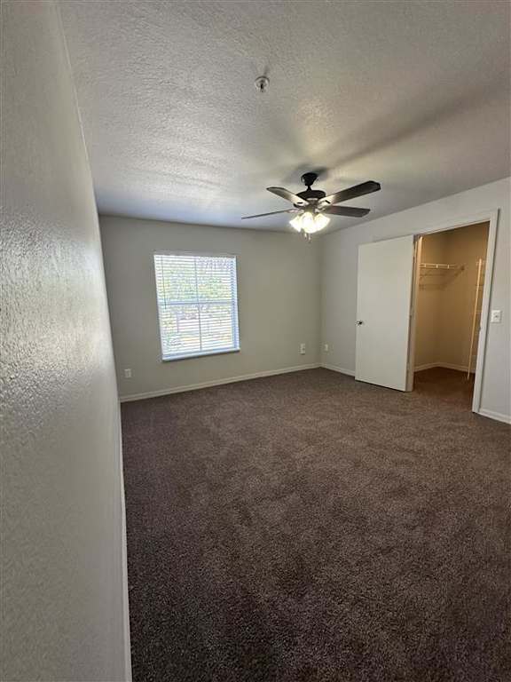 A room with a ceiling fan and carpeted floor.