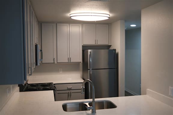 A kitchen with a stainless steel refrigerator and a sink.