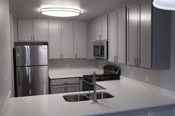 A kitchen with a stainless steel refrigerator and a black stove top oven.