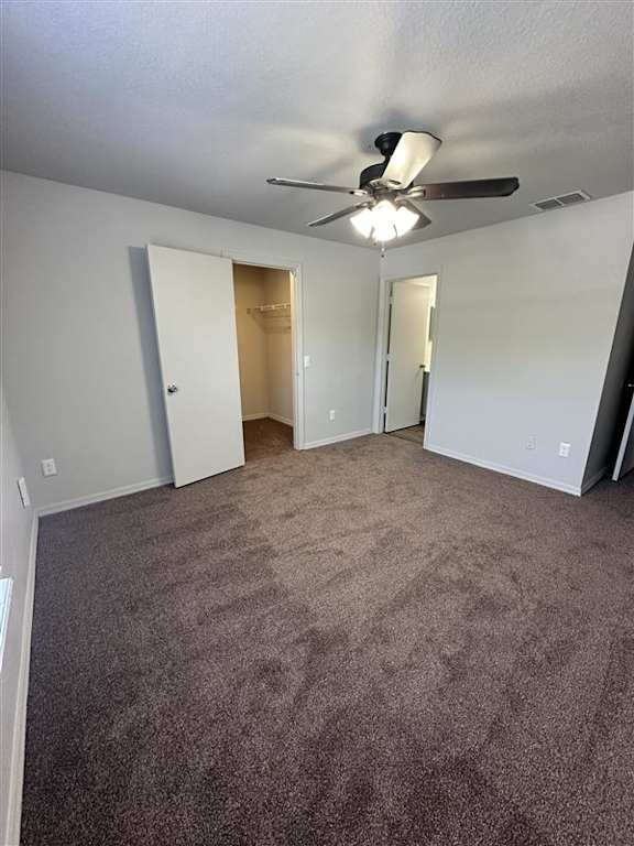 A room with a ceiling fan and carpeted floor.