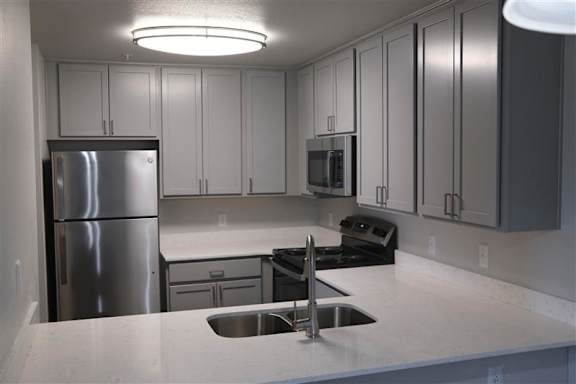 A kitchen with a stainless steel refrigerator and a black stove top oven.