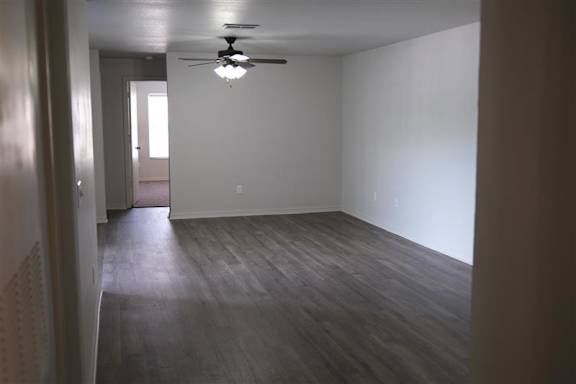 A room with a ceiling fan and wooden flooring.