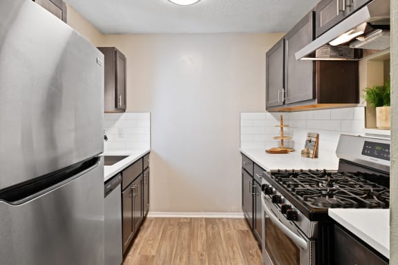 an empty kitchen with stainless steel appliances and white countertops
