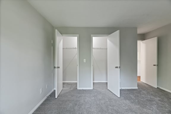 an empty room with three closets and a carpeted floor
