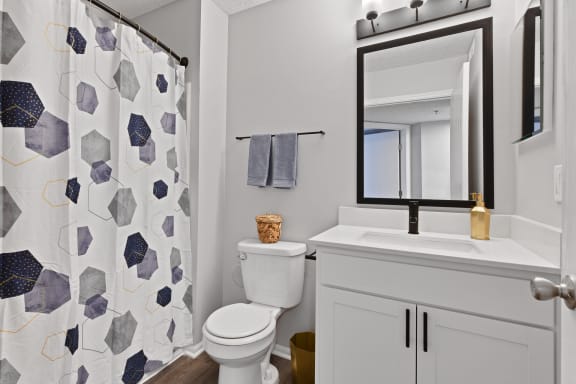a bathroom with a white sink and toilet next to a shower with a blue and white shower