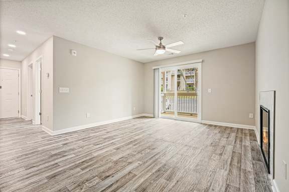A room with a ceiling fan and a sliding glass door leading to a balcony.