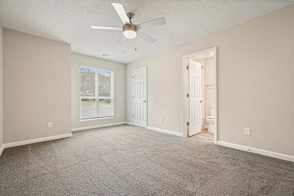 A room with a ceiling fan and carpeted floor.