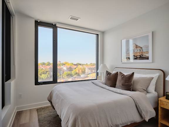 A bedroom with a large bed and a view of the city through the window.