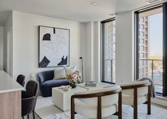 A modern living room with a blue sofa, a white coffee table, and a large abstract painting on the wall.