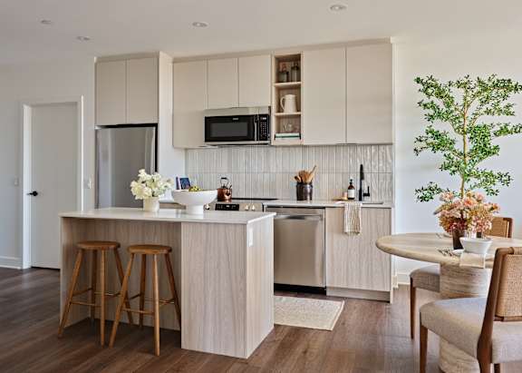 A kitchen with a white countertop and wooden bar stools.