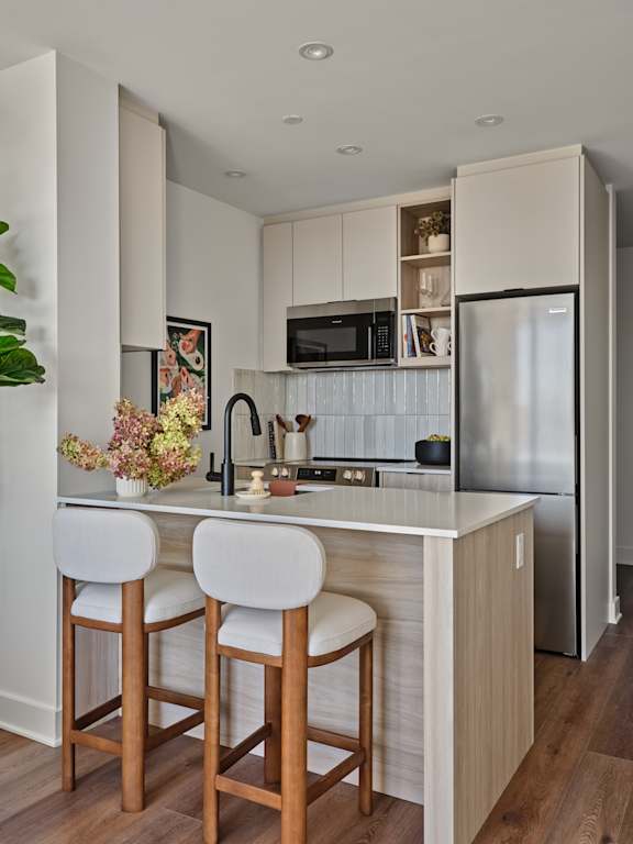 A kitchen with a white countertop and bar stools.
