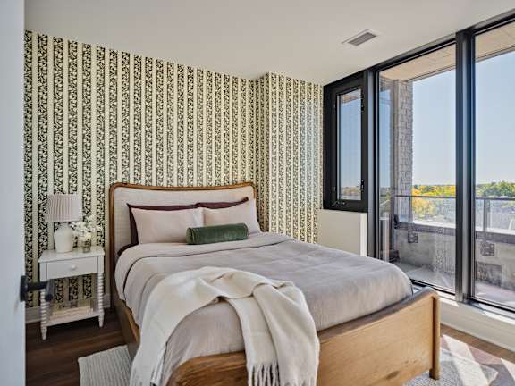 A bedroom with a large bed and a window overlooking a cityscape.