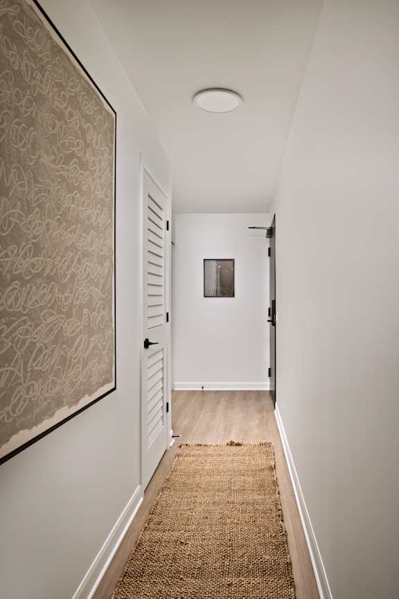 A hallway with a rug on the floor and a door on the right.