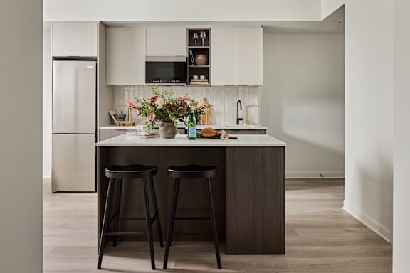 A kitchen with a white countertop and black bar stools.