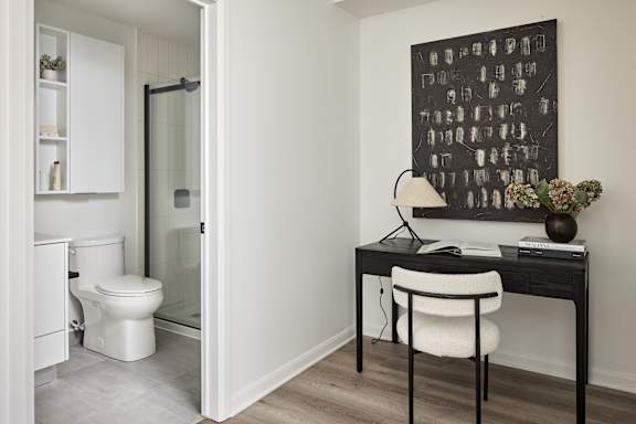 A white toilet is in a small bathroom next to a desk.